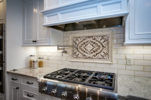 Kitchen counter and stainless steel stove with tile backdrop on the wall