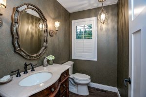 half bathroom with small window and chandelier
