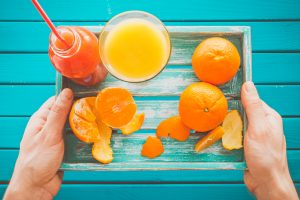 Man holds a vintage tray with mandarins and fresh juice in her hands. Top view