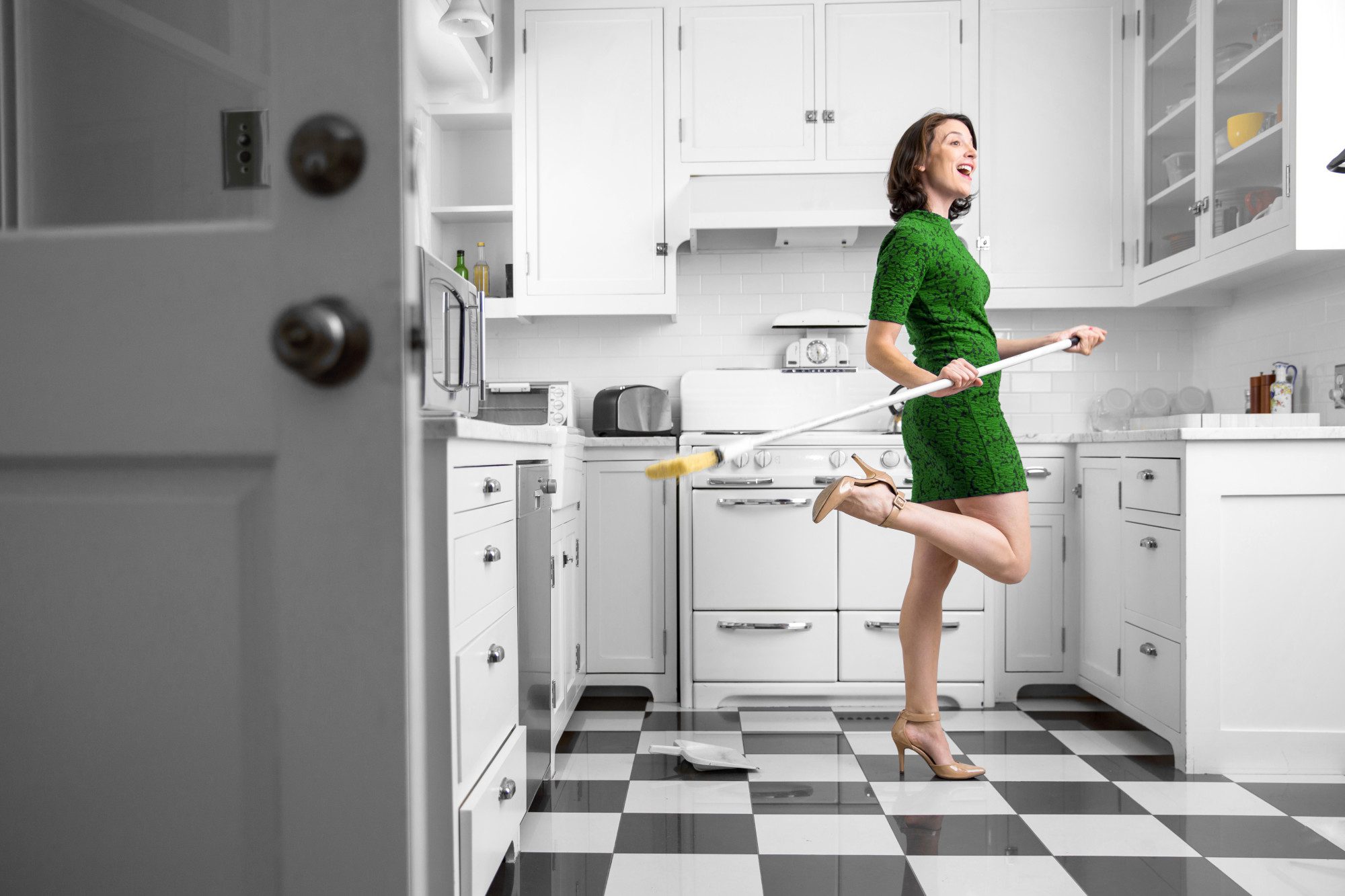 women dancing around joyfully with a broom in her kitchen
