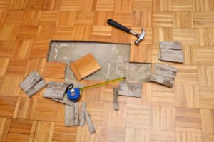 Renovation of damaged wooden floor of apartment, with hammer and measure tape
